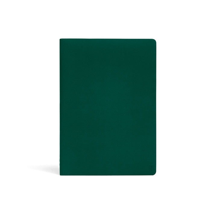 Karst A5 softcover stone paper notebook in forest green with rounded corners and subtle embossed logo, standing upright on a light gray background.
