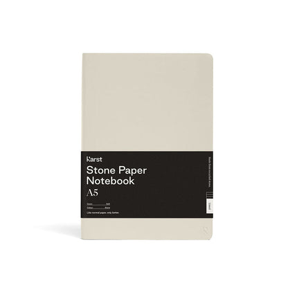 Karst Stone Paper Notebook A5 with a soft cream cover and rounded corners, wrapped in a black product band, photographed front-facing on a white background.