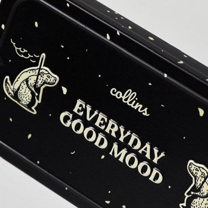 Close-up of a black Collins Everyday Good Mood incense tin with cream lettering, playful illustrated graphics, and speckled details in a bold modern home fragrance design.